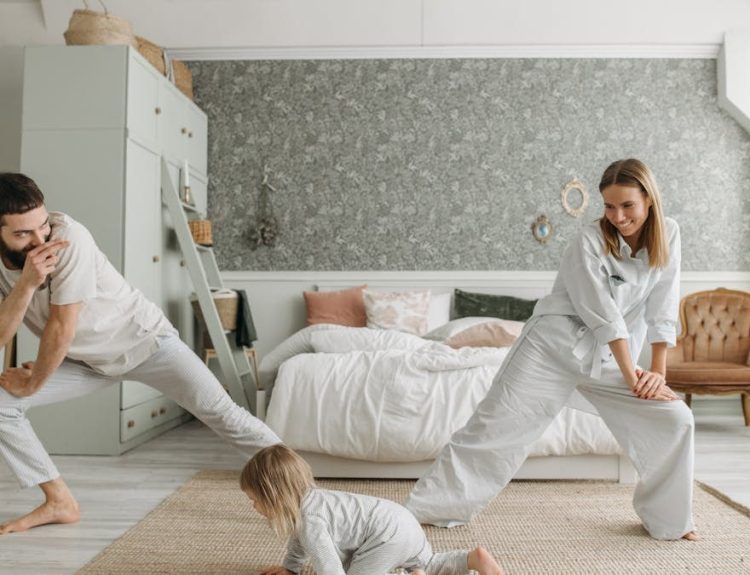A joyful family bonding through morning stretches in a cozy bedroom setting.